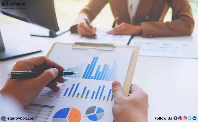 Hands reviewing printed bar and pie charts with a pen