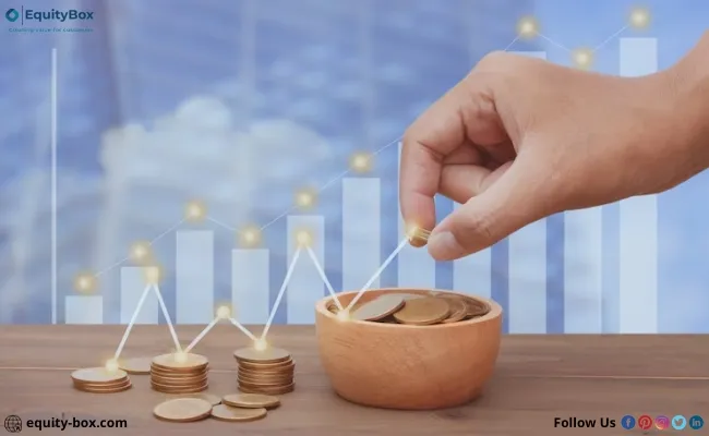 A hand placing a coin on stacks in front of a rising chart