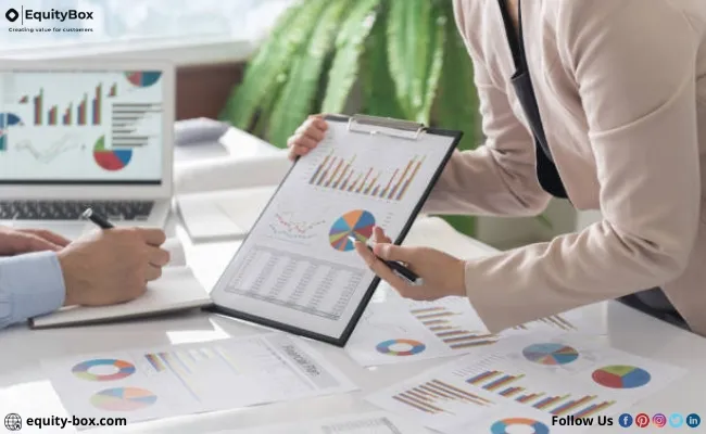 A person pointing a pen at printed charts on a clipboard
